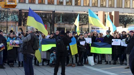 People-protest-Russian-war-in-Ukraine-with-flags-and-signs,-static