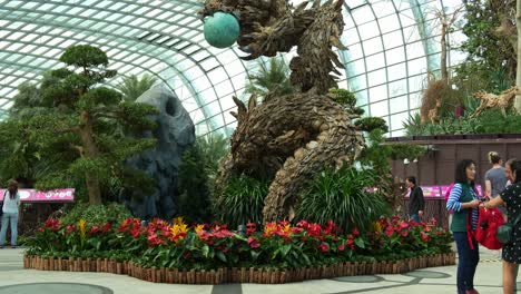 Escultura-De-Dragón-De-Madera,-Pieza-Central-Del-Invernadero-De-Cristal-Con-Cúpula-De-Flores-En-Los-Jardines-Junto-A-La-Bahía-Durante-La-Temporada-Festiva,-Para-Celebrar-El-Año-Nuevo-Lunar,-Toma-Inclinada-Del-Dragón