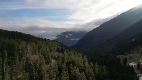 Obersee-Glarus-Näfels-Switzerland-flying-over-sunny-forest-towards-cloudy-valley