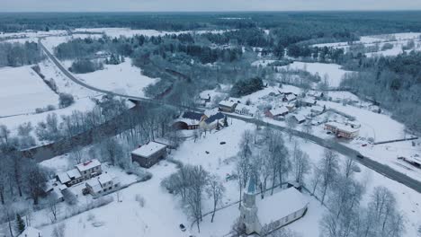 Snowy-Abava-river-near-Renda-village-during-winter,-serene-landscape,-aerial-view,-moving-forward