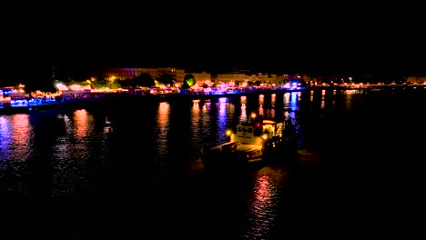 River-party-cruise-boat-and-Illuminated-Ferris-wheel-at-night-during-Wine-Fair,-Aerial-orbit-shot
