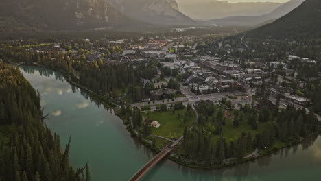 Banff-AB-Canada-Aerial-v18-flyover-town-capturing-pristine-Bow-river-with-turquoise-water,-quaint-townscape-with-forested-valleys-and-mountainous-surroundings---Shot-with-Mavic-3-Pro-Cine---July-2023