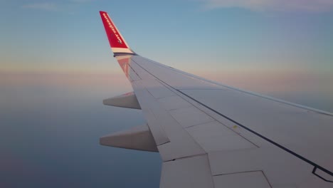 Wing-of-Norwegian-aircraft-and-cloudy-sky-seen-from-passenger-window