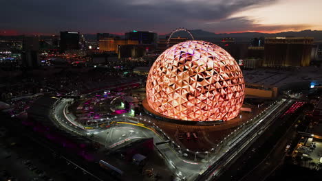 Drone-circling-the-night-lit-Sphere-entertainment-arena-in-Paradise,-Las-Vegas