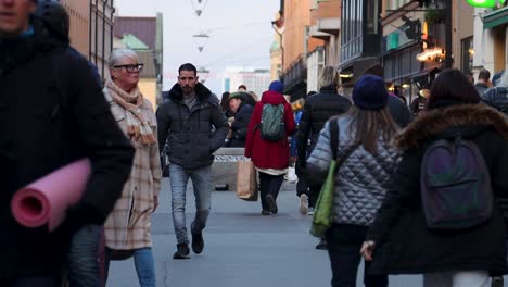 Man-with-cigarette-walks-on-busy-pedestrian-street-in-Stockholm,-slomo