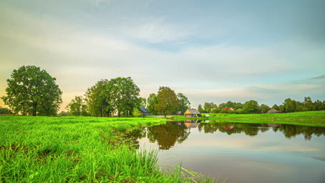 Paisaje-Escénico-Timelapse-Con-Reflejos-Del-Lago,-Tiro-De-ángulo-Bajo-Con-Hierba-Y-árboles-En-El-Horizonte