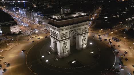 Triumphal-arch-with-Paris-cityscape-illuminated-at-night,-France