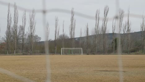 Empty-local-amateur-football-field-in-autumn-shot-behind-opponents-net-slow-motion-bokeh