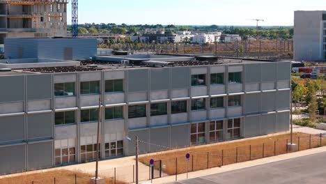 Toma-Aérea-En-órbita-De-Un-Nuevo-Edificio-De-Oficinas-Con-Un-Sitio-De-Construcción-Detrás