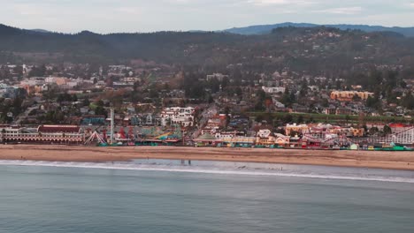 Telephoto-drone-shot-of-the-beach-and-rides-in-santa-cruz,-California