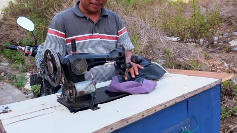 Smiling-man-sitting-on-a-scooter-on-a-attached-mobile-sewing-machine-giving-thumbs-up