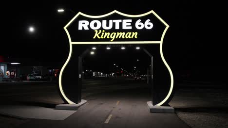 Großes-Route-66-Schild-Nachts-In-Kingman,-Arizona-Mit-Vorbeifahrenden-Fahrzeugen-Und-Stabilem-Video