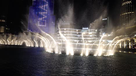 Fuente-Musical-En-El-Centro-De-Dubai,-Emiratos-Árabes-Unidos,-Por-La-Noche-Frente-Al-Burj-Khalifa,-Iluminación,-Rociado-De-Agua-Y-Luz.