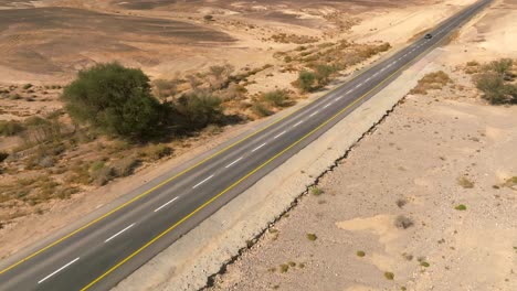 Car-zooming-by-heading-north-on-a-Desert-highway-with-cloudy-blue-sky