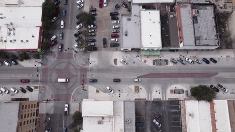 Busy-downtown-intersection-in-San-Angelo,-Texas,-traffic-drives-through-a-light