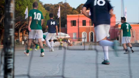 Zeitlupen-Kamerafahrt-Von-Straßenfußballspielern-Mitten-Im-Spiel-Durch-Löcher-Im-Tornetz