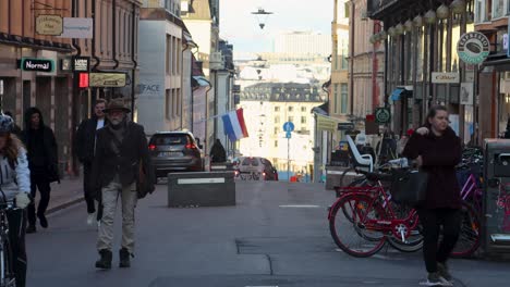 People-ride-bikes-and-walk-on-pedestrian-street-in-Stockholm,-Sweden