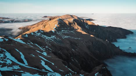 Timelapse-of-mountain-peaks,-with-snow-patches-on-its-slopes,-emerging-above-clouds-during-cloud-inversion-in-the-Massif-Central-Auvergne-Volcanoes-National-Park-in-France