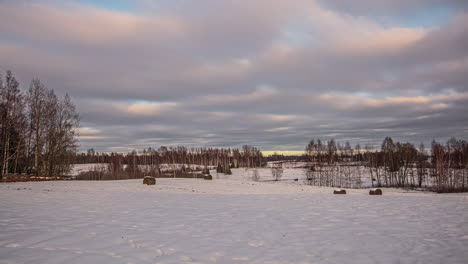 Zeitraffer-Von-Wolken,-Die-über-Ein-Schneebedecktes-Feld-Mit-Vereinzelten-Bäumen-Ziehen