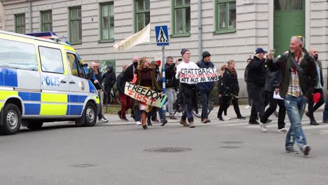 Demonstranten-Mit-Schildern-Und-Fahnen-Gehen-An-Einem-Polizeiwagen-In-Stockholm-Vorbei