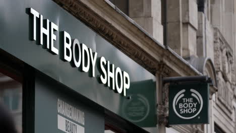 In-slow-motion-people-walk-past-The-Body-Shop-store-sign-on-Oxford-Street