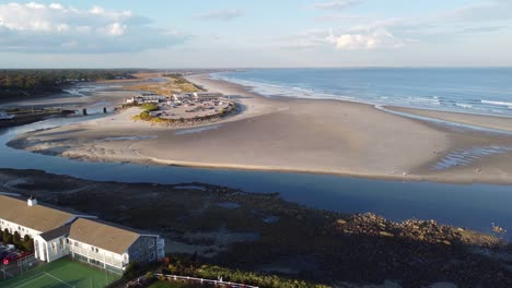 Aerial-view-of-resort-beach-town-Ogunquit-on-Maine-USA-coastline-drone-rotate-around-waterfront-hotel-building-and-sandy-beach