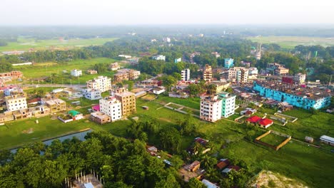 Vista-Aérea-Que-Establece-Una-Colorida-Propiedad-De-Complejo-De-Apartamentos-En-Bangladesh-En-Un-Exuberante-Paisaje-Suburbano-Verde