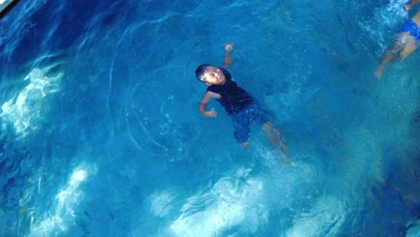 Draufsicht-Auf-Ein-Schwimmendes-Kind-Auf-Dem-Rücken-Im-Pool-Des-Ferienhauses,-Dynamisch