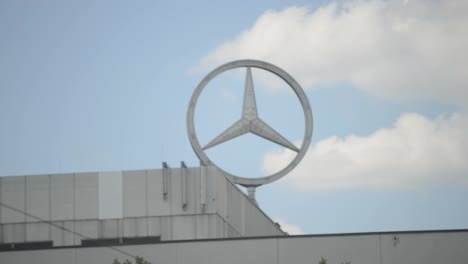Mercedes-Benz-logo-on-top-of-office-building-against-blue-sky