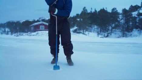 Man-Making-A-Hole-In-An-Iced-Lake-For-Fishing---Close-Up