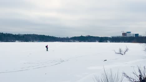 Un-Patinador-Sobre-Hielo-Solitario-Patina-Sobre-Un-Río-Helado-Y-Nevado-En-Estocolmo-Nublado