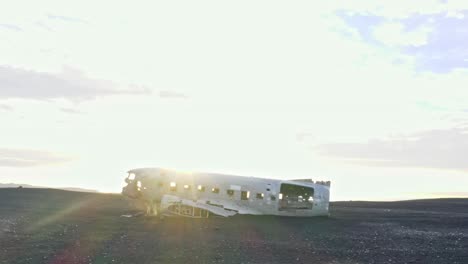 Aerial-cinematic-4K-drone-footage-captures-a-crashed-airplane-scene-in-Iceland,-offering-a-dramatic-sunray