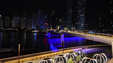 Dubai,-Vereinigte-Arabische-Emirate,-Futuristische-Nachtlandschaft,-Lichter-Auf-Den-Kapseln-Am-Wasser-Und-Der-Bluewaters-Brücke