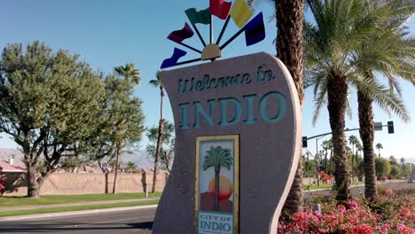 Welcome-to-Indio,-California,-City-of-Festivals-sign-medium-shot-and-tilt-down-with-vehicles-driving-by
