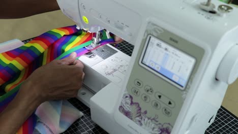 Person-sewing-with-sewing-machine-a-multicolored-rainbow-textile