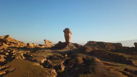 Fly-over-a-single-alone-pillar-wind-erosion-rock-cliff-geology-erosion-in-desert-climate-in-Iran-natural-wonderful-scenic-landscape-in-summer-sunset-time-blue-sky-and-wild-nature-road-trip-in-Iran