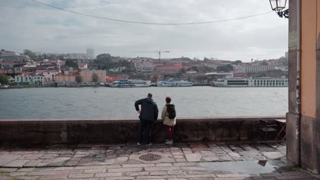 Romantic-Couple-Discussing-and-Pointing-at-Porto's-Waterfront-along-River-Douro,-Exploring-Scenic-City-Spots-Together