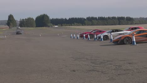 Static-shot-of-supercars-parked-up-in-the-pit-lane-with-cars-racing