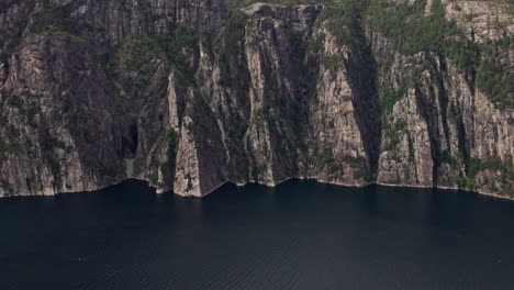 Aerial-shot,-pushing-in-on-the-cliffs-beneath-Preikestolen,-by-Lysefjord-in-Norway