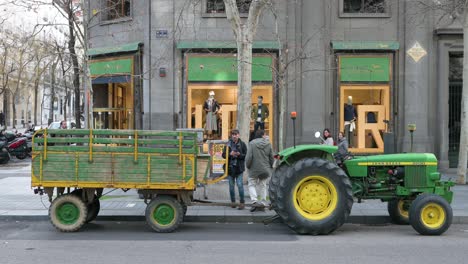 In-Einer-Einkaufsstraße-Mit-Luxuseinkaufszentren-In-Madrid-Parkt-Ein-Landwirtstraktor,-Wo-Landwirte,-Arbeiter-Und-Gewerkschaftsmitglieder-Gegen-Unlauteren-Wettbewerb-Und-Agrarpolitik-Protestieren.