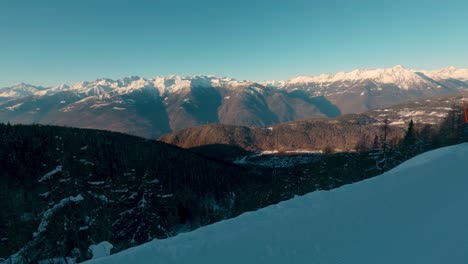 View-of-a-snowy-valley-with-a-village-from-a-ski-slope-in-the-Alps,-wide-view