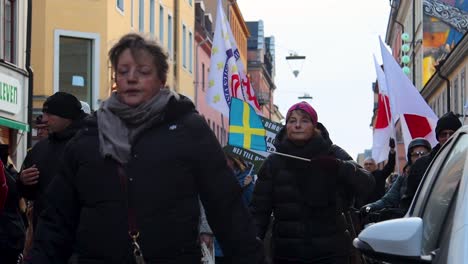 Woman-waves-Swedish-flag-at-covid-regulation-protest-march,-Stockholm