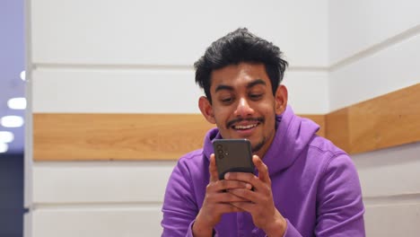 Mann-Aus-Sri-Lanka-Hört-Seinem-Freund-Zu,-Redet-Und-Schaut-Auf-Sein-Smartphone,-Hochformat