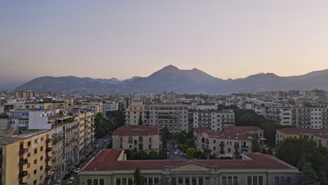 Palermo-Italy-Aerial-v1-flyover-Via-Isonzo-capturing-cityscape-of-urban-neighborhoods-at-sunset-dusk-with-mountains-on-the-skyline-and-birds-flying-across-the-scene---Shot-with-Mavic-3-Cine---May-2023