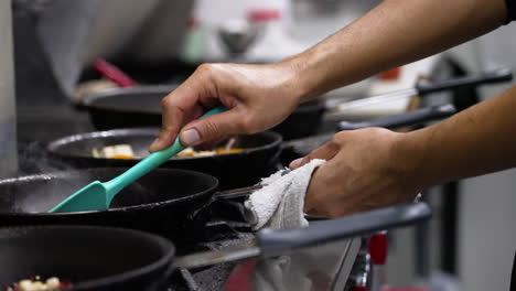 Cocinero-De-Restaurante-Profesional-Maneja-Múltiples-Sartenes-Y-Voltea-Los-Ingredientes-En-Una-Sartén-En-La-Estufa-De-La-Cocina-Comercial,-Cierre-En-Cámara-Lenta-4k