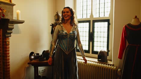 Wide-view-of-an-attractive-woman-dressed-up-in-a-warrior-princess-costume-standing-in-an-medieval-armory-and-laughing