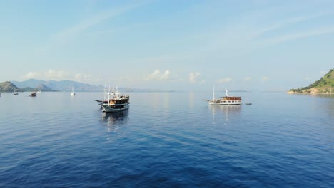 Eine-Gruppe-Von-Drei-Kreuzfahrtschiffen-Schwimmt-Auf-Ruhigen-Gewässern-In-Der-Nähe-Der-Insel-Pulau-Kelor,-In-Der-Nähe-Der-Insel-Komodo,-Und-Präsentiert-Die-Ruhige-Schönheit-Indonesiens-Und-Asiens