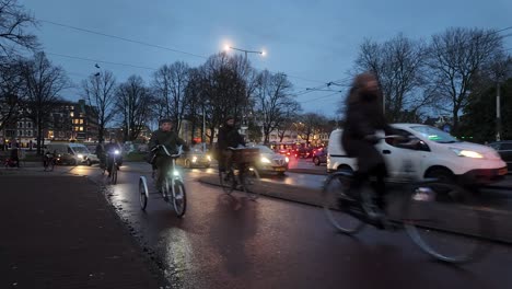 Weite-Sicht-Auf-Radfahrer-Und-Autos,-Die-Abends-Auf-Stark-Befahrenen-Straßen-Von-Amsterdam,-Niederlande,-Fahren