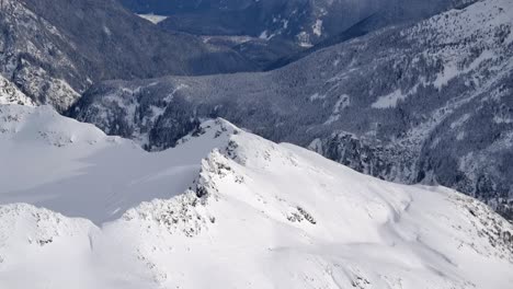 Sonnige-Bergtal-Winterlandschaft-Und-Schneebedeckte-Gipfel-Aus-Der-Luft