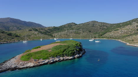 Aéreo:-Volando-Bajo-Hacia-La-Bahía-Tropical-De-La-Isla-De-Kira-Panagia-En-Esporadas,-Grecia-Con-Muchos-Veleros-Y-Catamaranes